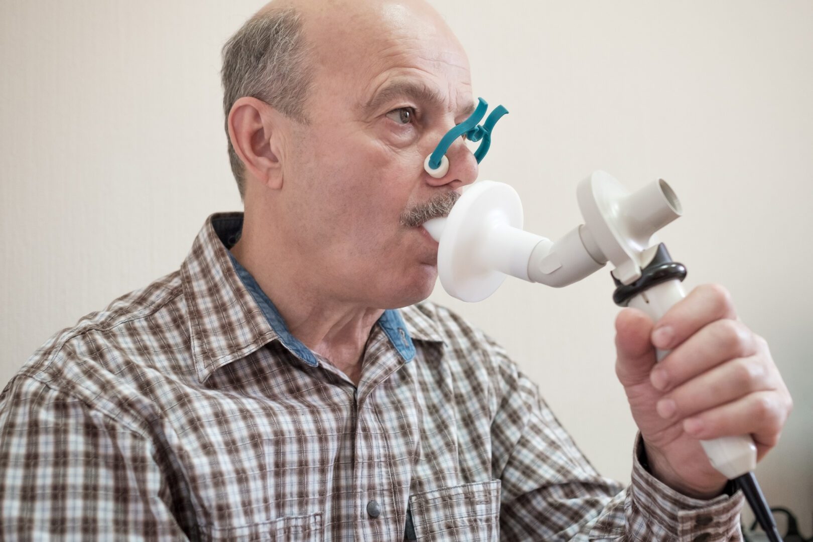 Senior hispanic man man testing breathing function by spirometry. Diagnosis of respiratory function in pulmonary disease