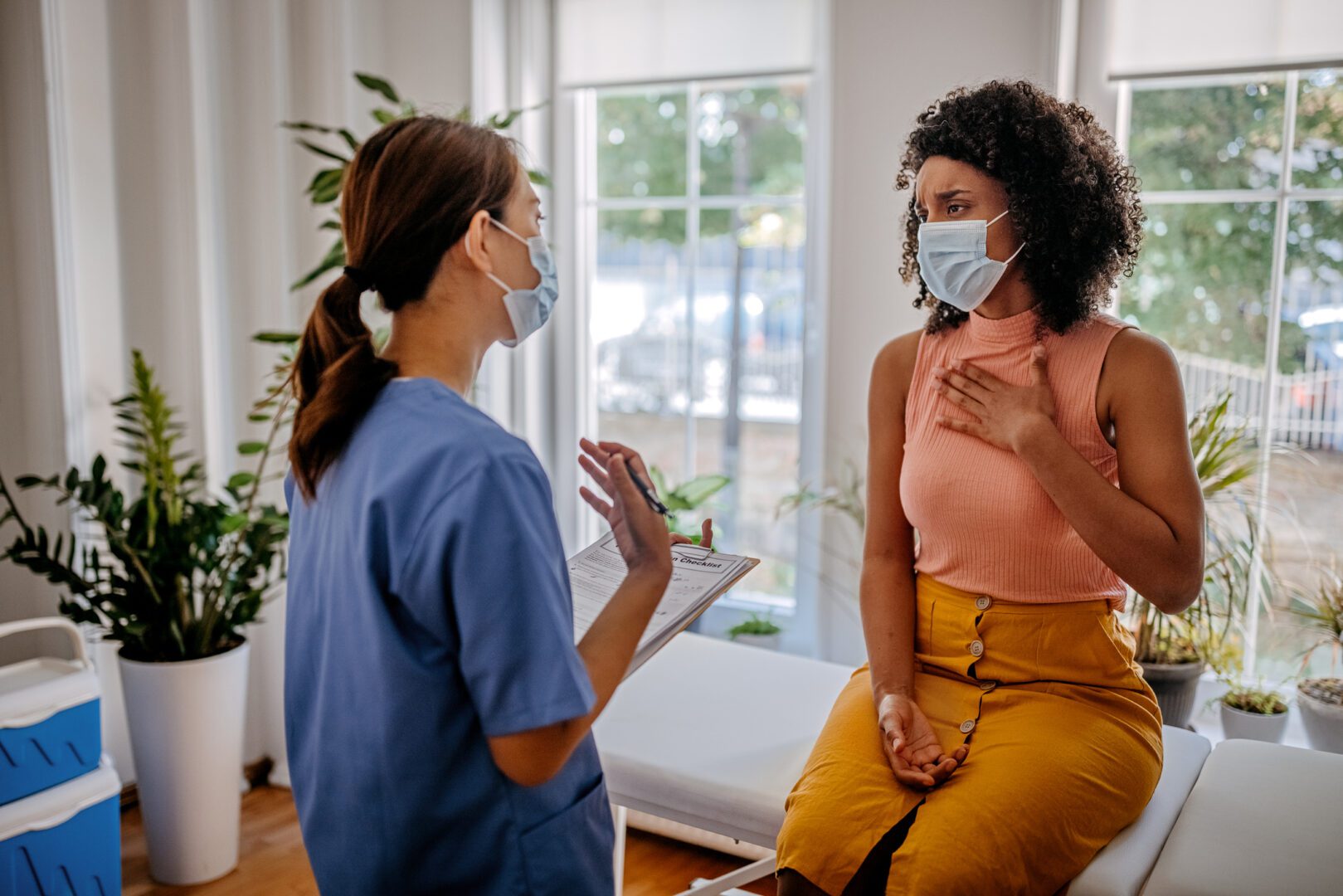 Nurse talking with her patient while female doctor update information about patient before vaccination.