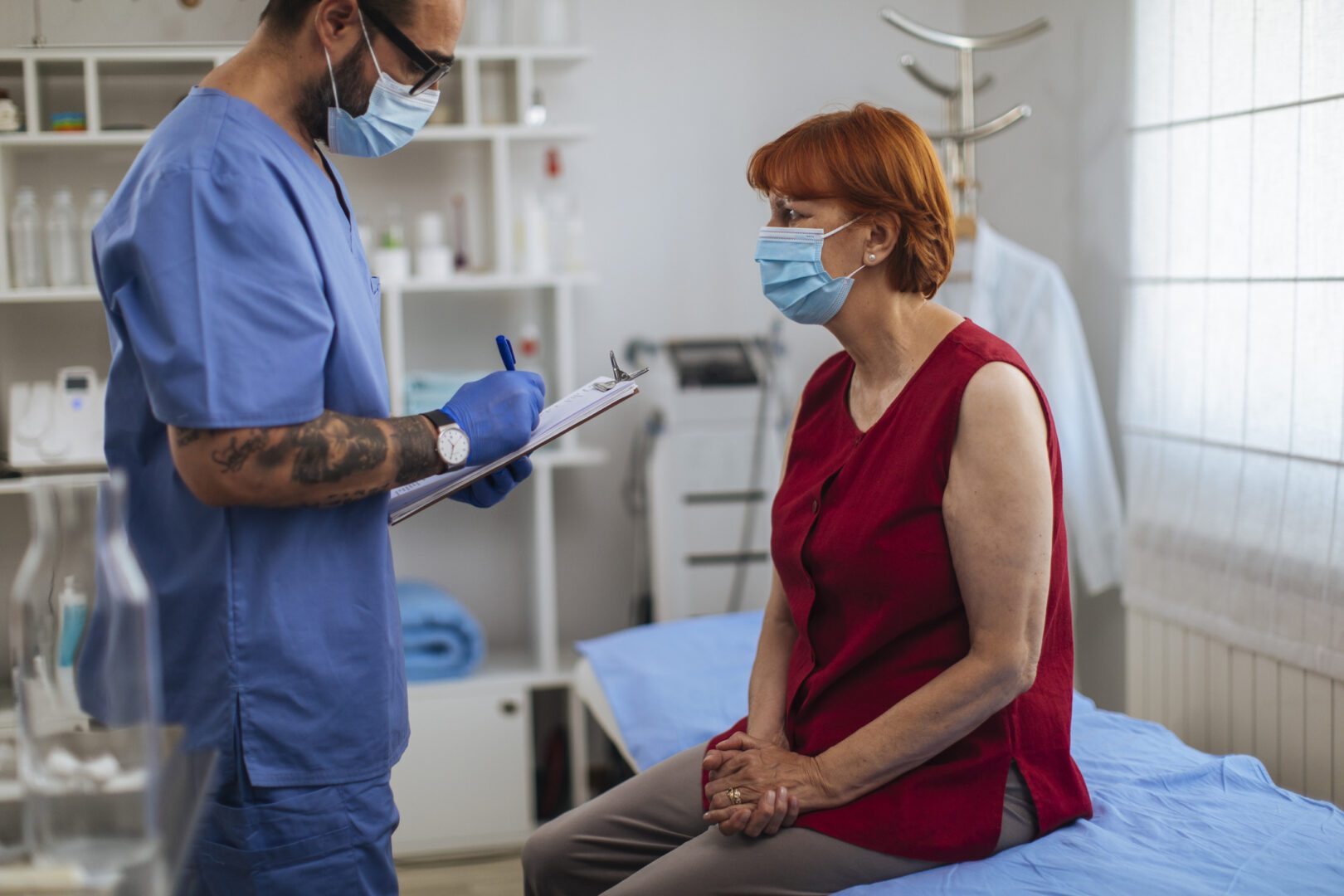 Senior red head talking to her doctor while he is filling up a medical form