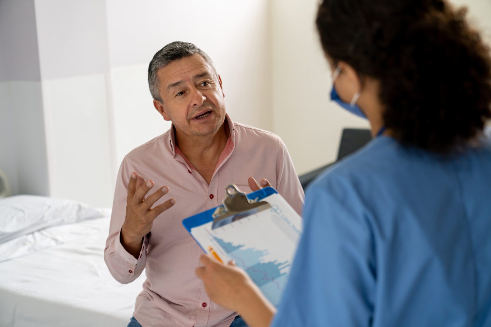Patient talking to a nurse and asking questions before a procedure at the hospital - healthcare and medicine concepts