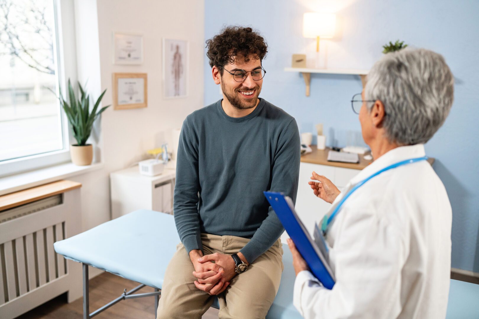 Young Caucasian male patient having an annual medical check-up with an senior Caucasian female doctor, at the ordination