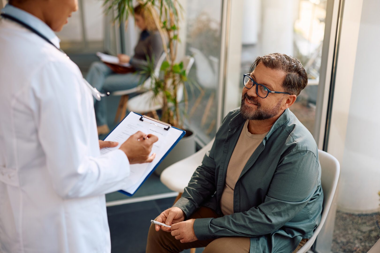 Happy mature man communicating with a doctor in waiting room at the clinic.