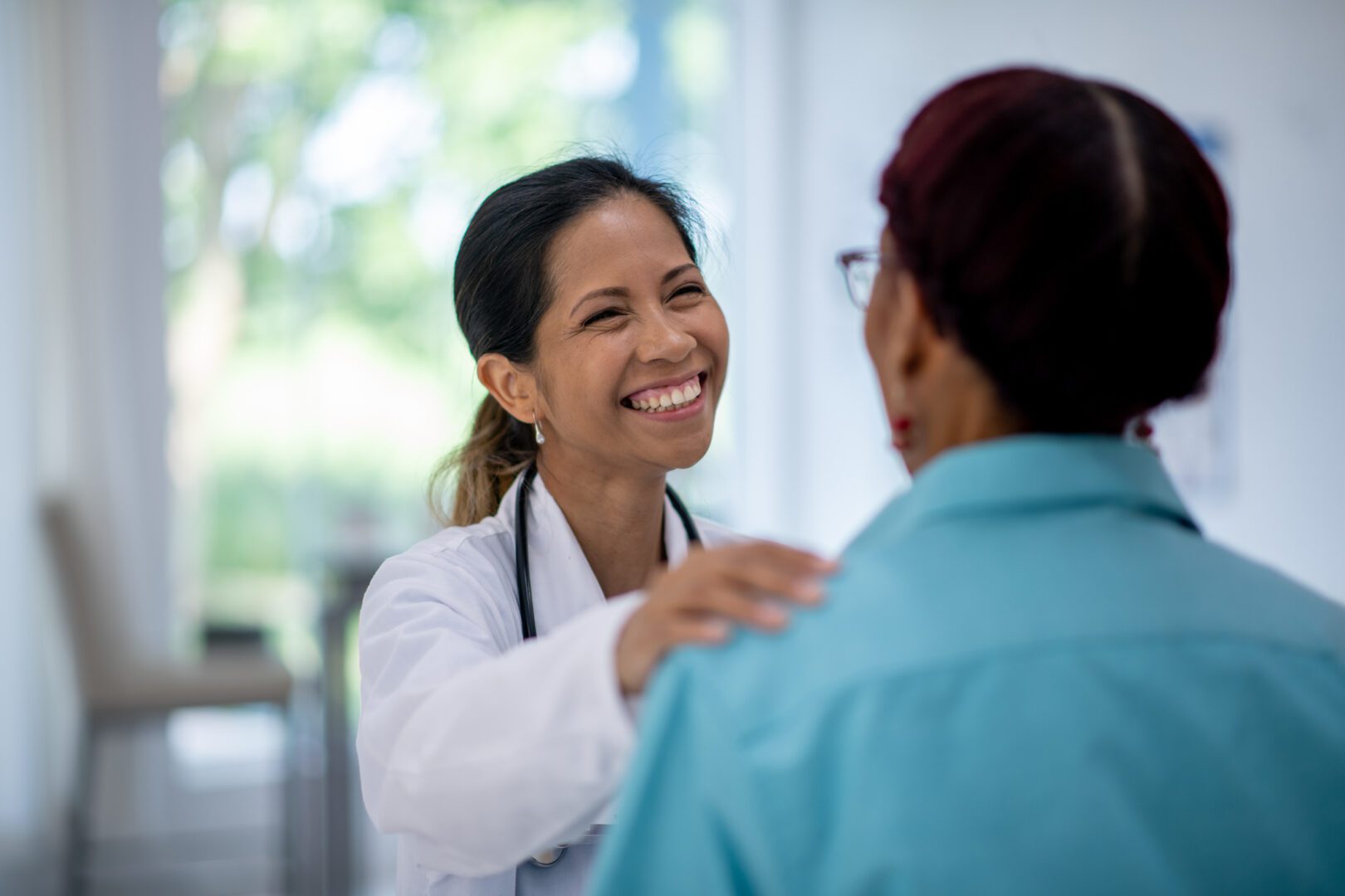 Healthcare worker assuring a patient, promoting understanding and trust during a consultation in a sunny clinic.