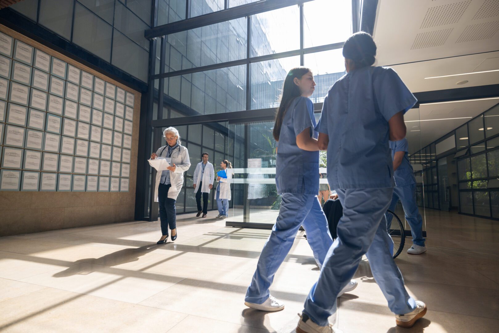 Group of Latin American healthcare workers walking through an entrance hall at a hospital - healthcare and medicine concepts