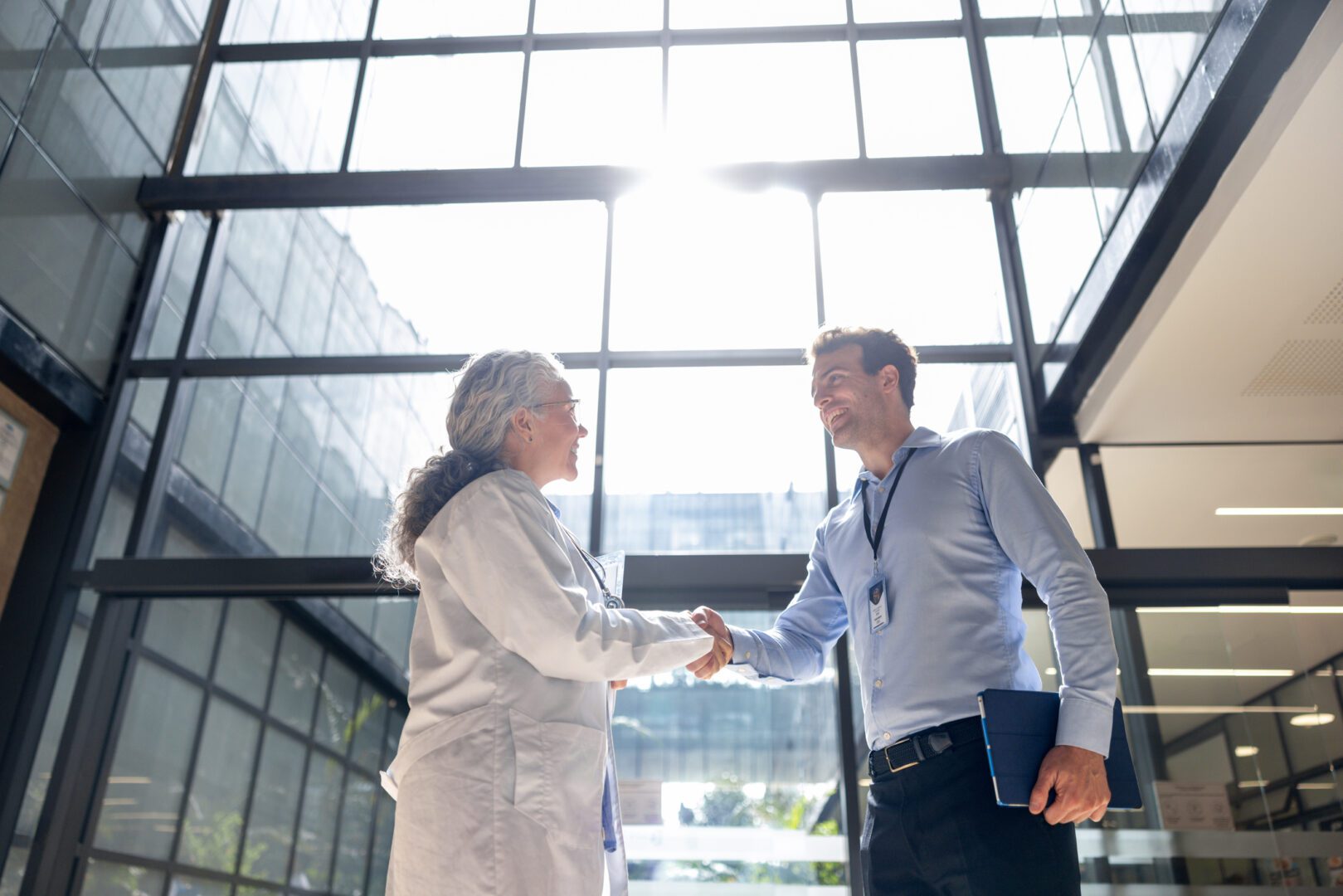 Medical sales representative greeting a doctor with a handshake at the hospital and smiling - healthcare and medicine concepts
