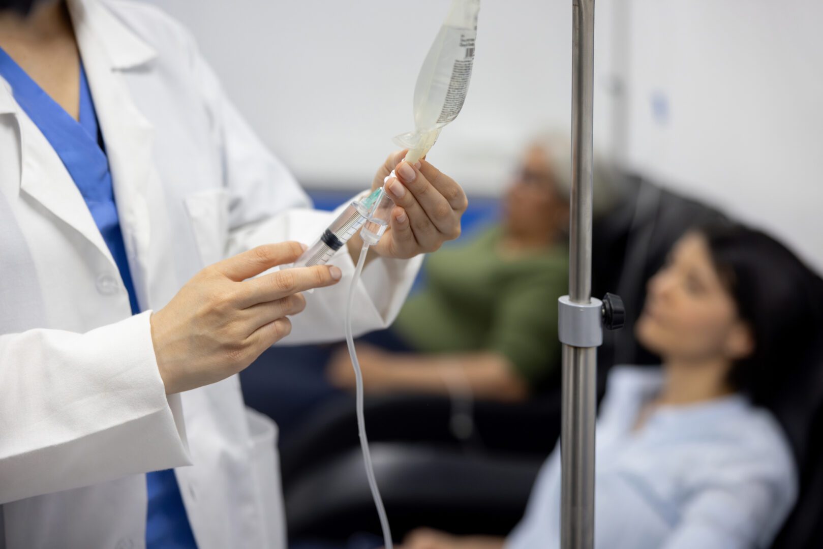 Doctor putting medicine on an patients IV drip at the hospital - healthcare and medicine concepts