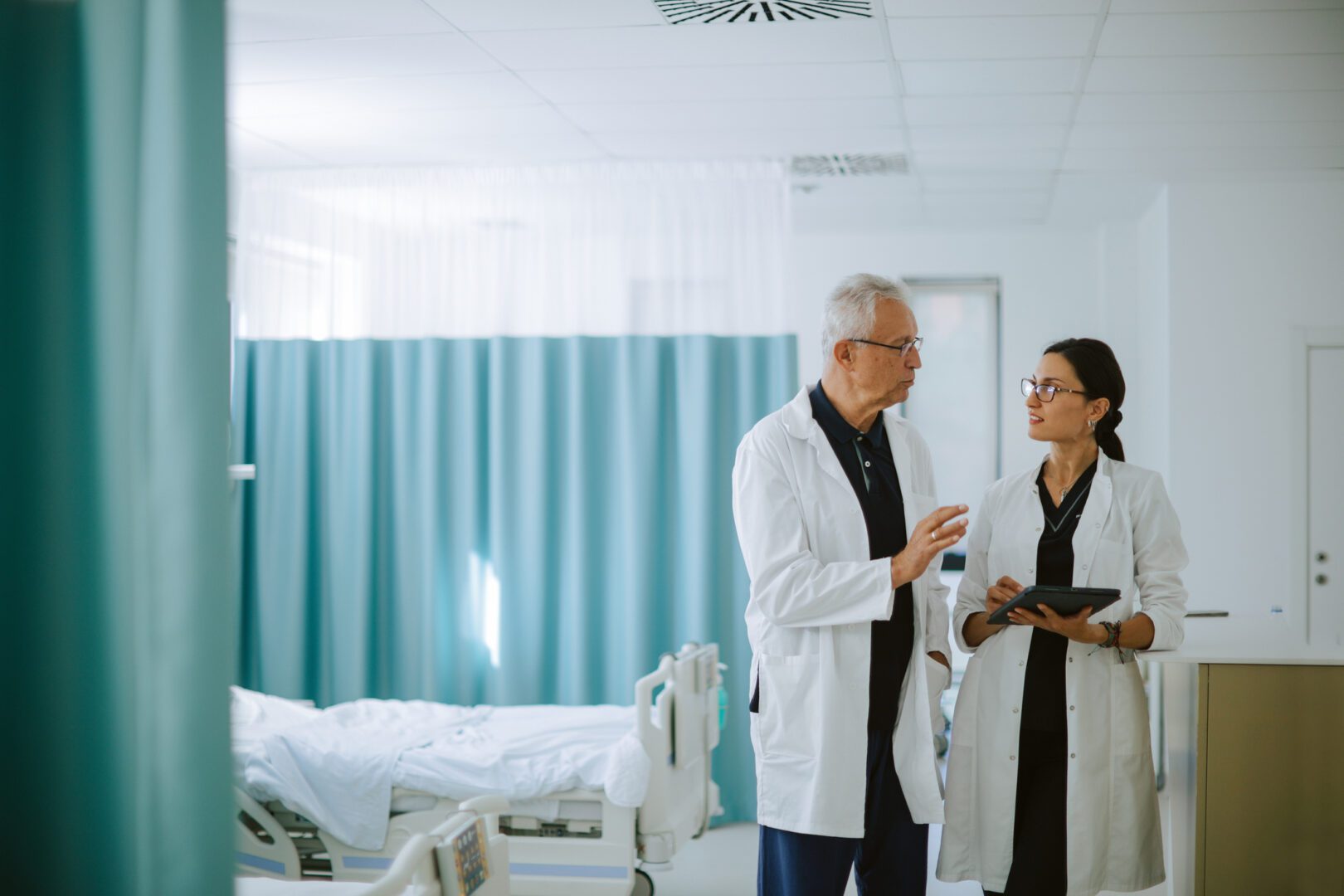 Male and female doctors analyzing patient information on a tablet to coordinate medical procedures. Digital AI powered tools enhance workflow efficiency and support accurate, data-driven decision-making in modern healthcare.