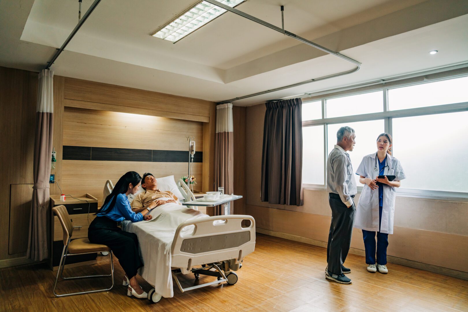 Medical doctor explaining patient condition to family in hospital ward during healthcare consultation and care