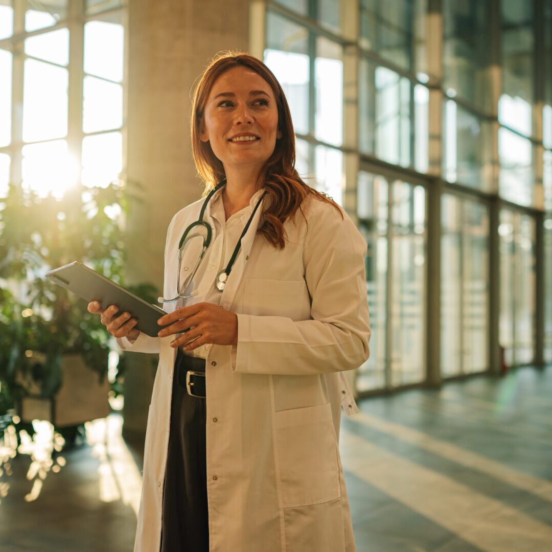 Confident doctor using a digital tablet, enjoying a fulfilling role in a modern hospital environment, radiating positivity and professionalism
