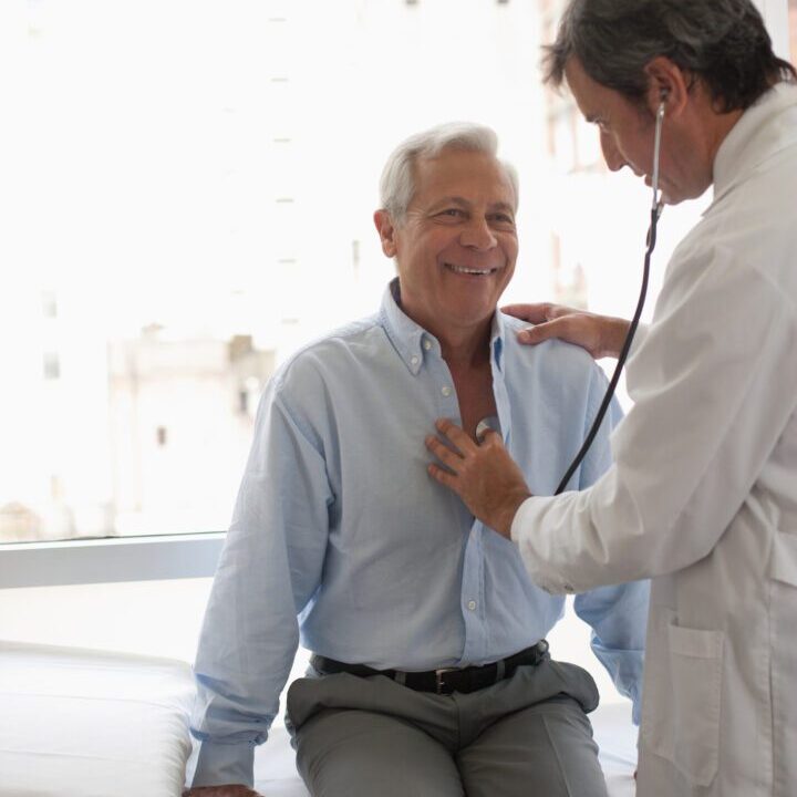 Doctor using stethoscope on smiling patient